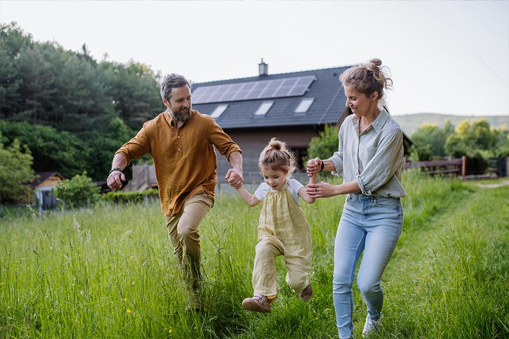 gezin met dochter geniet van natuur in het gras voor hun huis uitegerust met zonnepanelen van Energreen